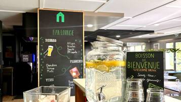 A bar lounge area with a menu board listing drinks and a welcome drink sign.