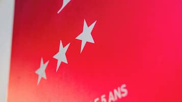 Un letrero rojo con texto y estrellas blancos, que indica el quinto aniversario del Ministerio de Turismo.