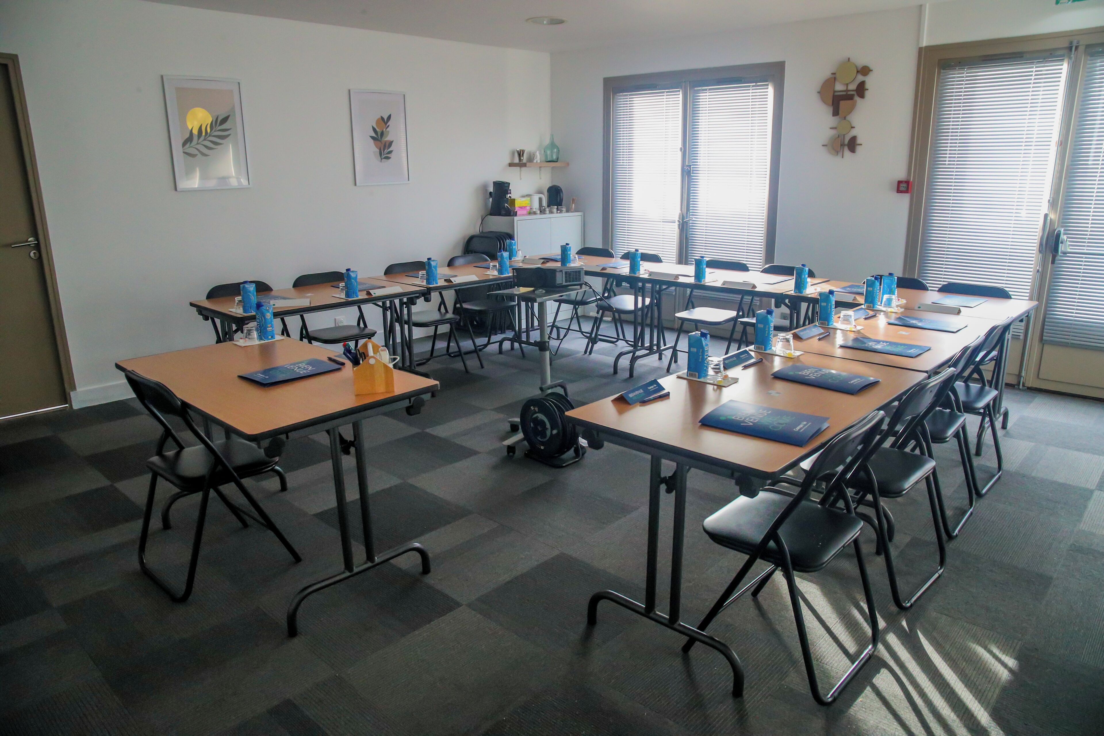 Une salle de conférence dotée de plusieurs tables et de chaises, ainsi que de bouteilles d’eau et de carnets.