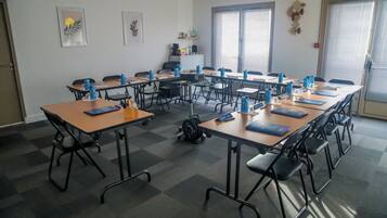 Une salle de conférence dotée de plusieurs tables et de chaises, ainsi que de bouteilles d’eau et de carnets.