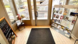 A hotel entrance with a glass door, a small reception desk, a blackboard with names, and a display of brochures. - Hotel Campanile Montargis - Amilly (Amilly)