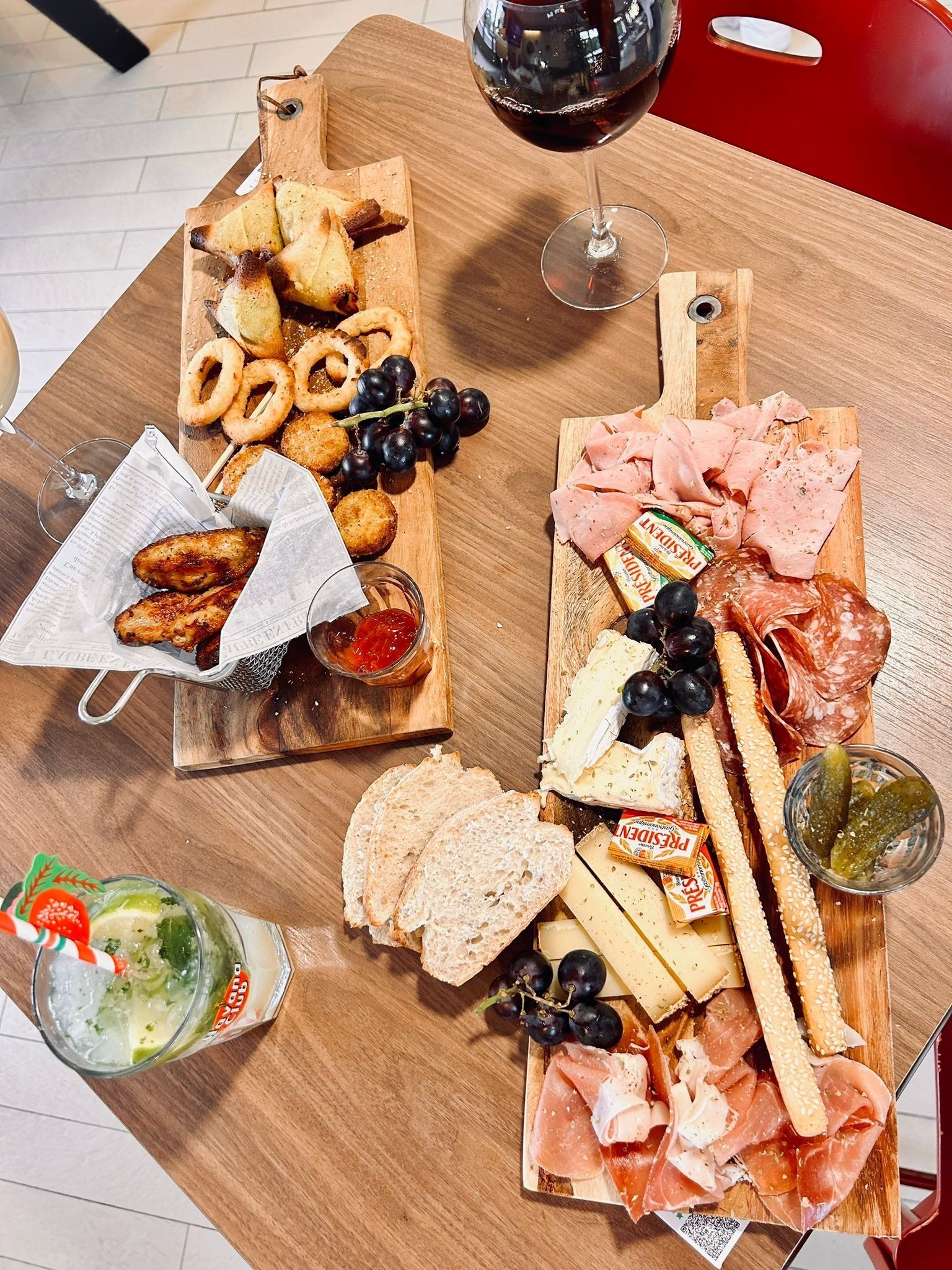 A wooden board with various cheeses, meats, and bread.