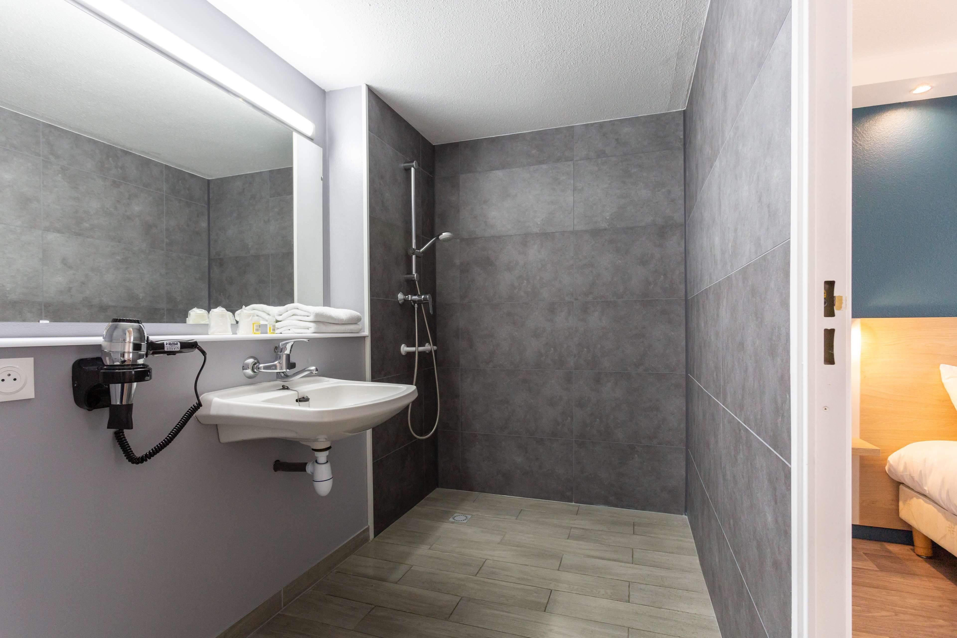 A modern bathroom with a sink, mirror, and shower.