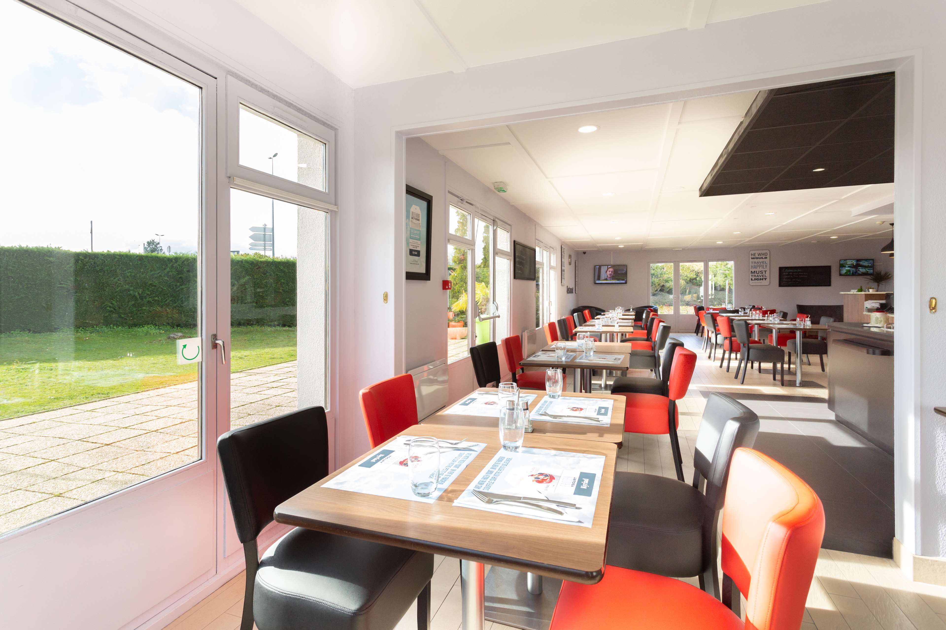 Un comedor moderno con mesas y sillas, ventanas amplias y vistas al exterior.
