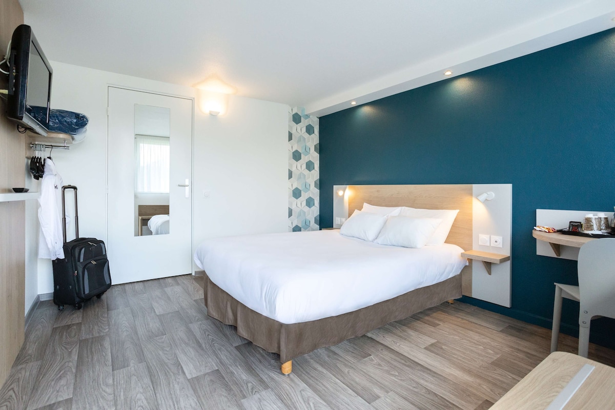 Una habitación de hotel moderna con una cama grande, un escritorio y un televisor.