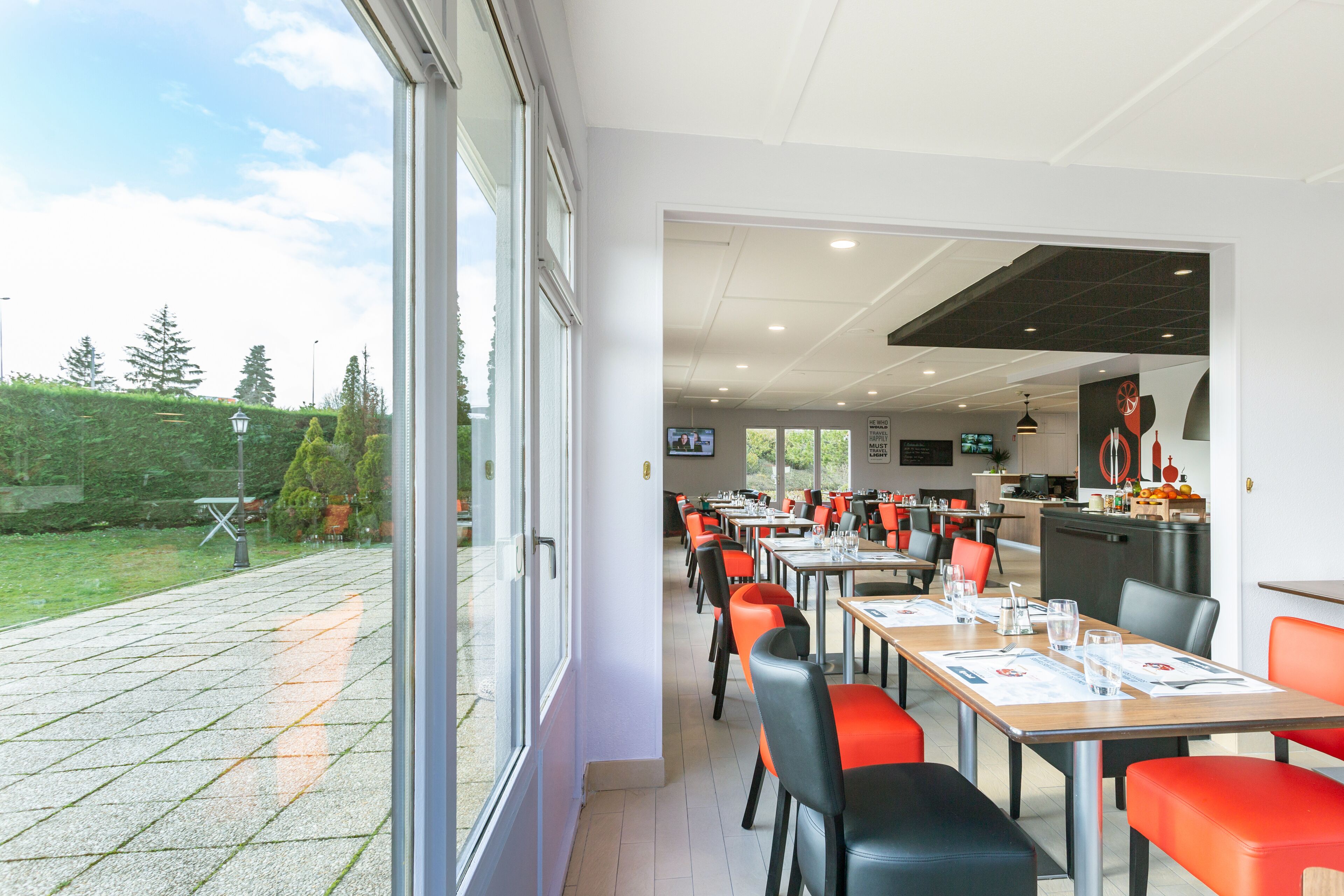 A restaurant with outdoor seating, tables with menus, and a view of the garden.