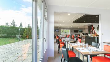 A restaurant with outdoor seating, tables with menus, and a view of the garden.