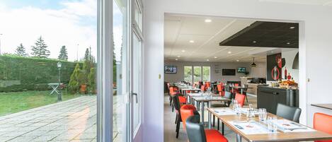 A restaurant with outdoor seating, tables with menus, and a view of the garden.