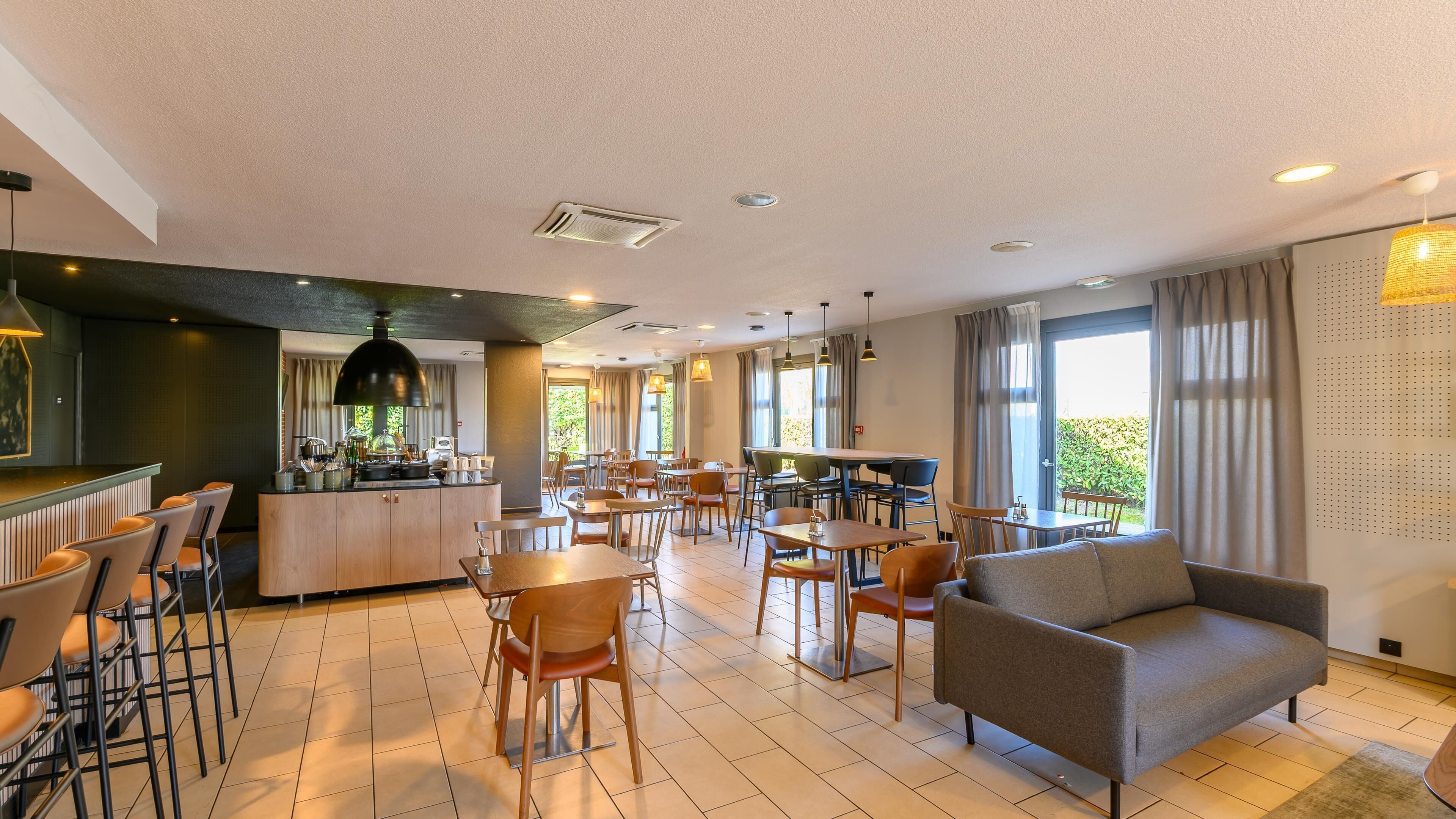 Un hall d’hôtel moderne doté d’un bar, d’un espace repas et de coins salon.