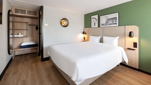A hotel room with a large bed, a wardrobe, a mirror, and two framed pictures on the wall. - Campanile NATURE - Epône (Epone)