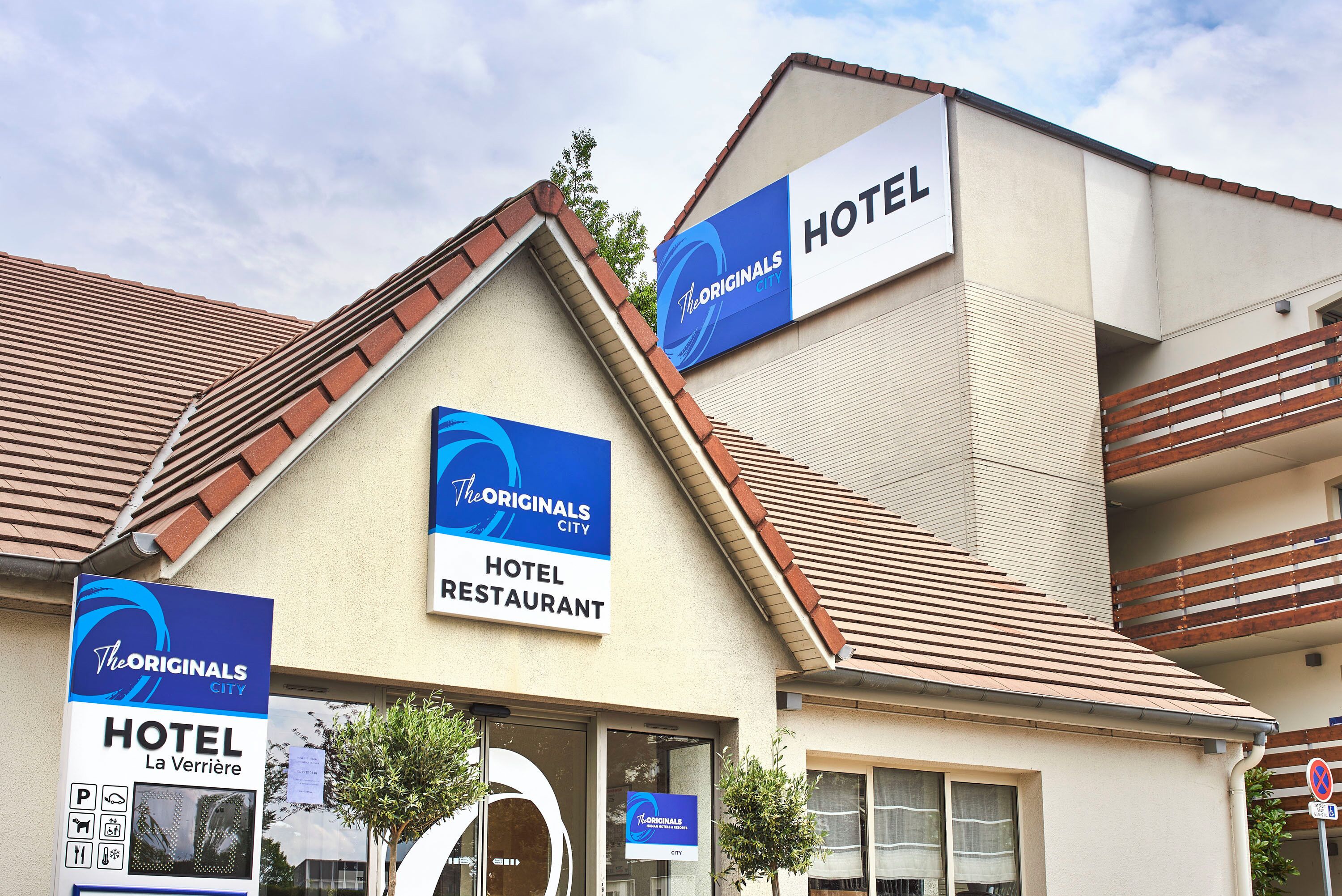 A hotel with signs indicating it is part of The Originals City hotel and restaurant complex.