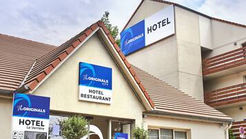 A hotel with signs indicating it is part of The Originals City hotel and restaurant complex.