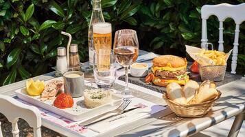 A table set outdoors with a variety of foods, drinks, and a bottle of beer.