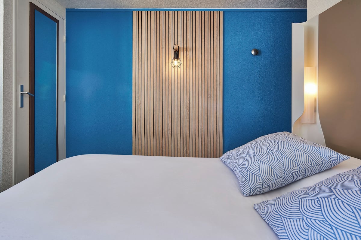 Ein Hotelzimmer mit Bett, einer Wand aus Holzpaneelen und einer blauen Akzentwand.