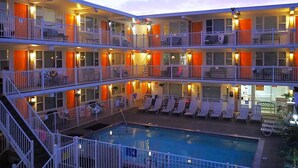 A multi-story hotel with balconies, a pool, and lounge chairs. - Esplanade Suites, a Sundance Vacations Property (Wildwood)