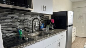 A modern kitchen with a granite countertop, stainless steel appliances, and a tiled backsplash. - Esplanade Suites, a Sundance Vacations Property (Wildwood)