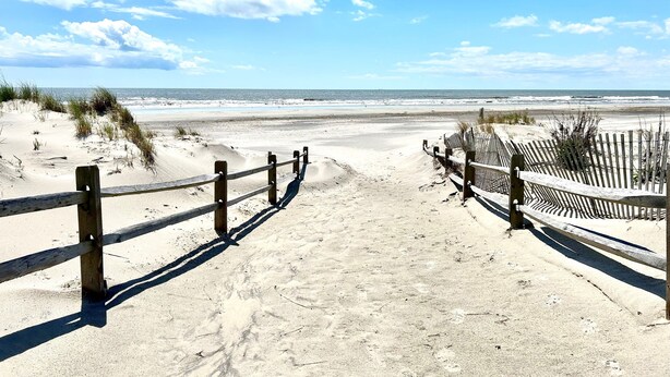 A sandy beach path leading to the ocean, with wooden fences on either side. - Esplanade Suites, a Sundance Vacations Property (Wildwood)