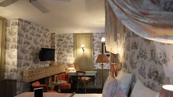 Een hotelkamer met een bed, een bureau, een stoel, een televisie en een open haard.