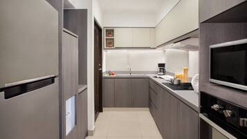 A modern kitchen with grey cabinetry, a stainless steel refrigerator, a built-in oven, and a microwave.