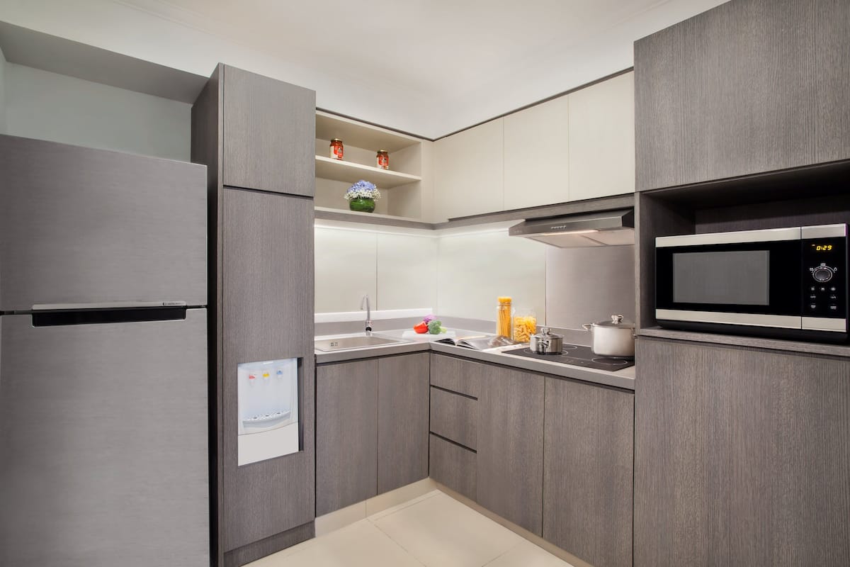 Une cuisine moderne avec des meubles de couleur grise, un réfrigérateur en acier inoxydable, un four à micro-ondes et un évier avec un robinet.