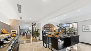 Een moderne hotellobby met een marmeren vloer, een receptiebalie en een buffetruimte.