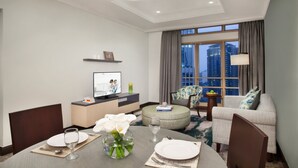 Een hotelkamer met een zithoek, een bank, een televisie en uitzicht op de stad.