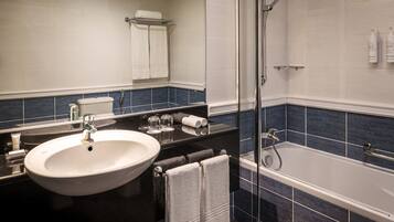 A bathroom with a white sink, black countertop, and a bathtub.