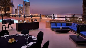 An outdoor dining area with a pool, barbecue, and seating.