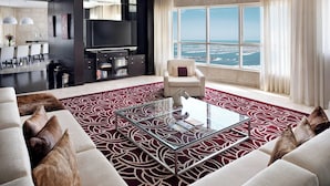 A modern living room with a glass coffee table, a sofa, and a view of the sea.