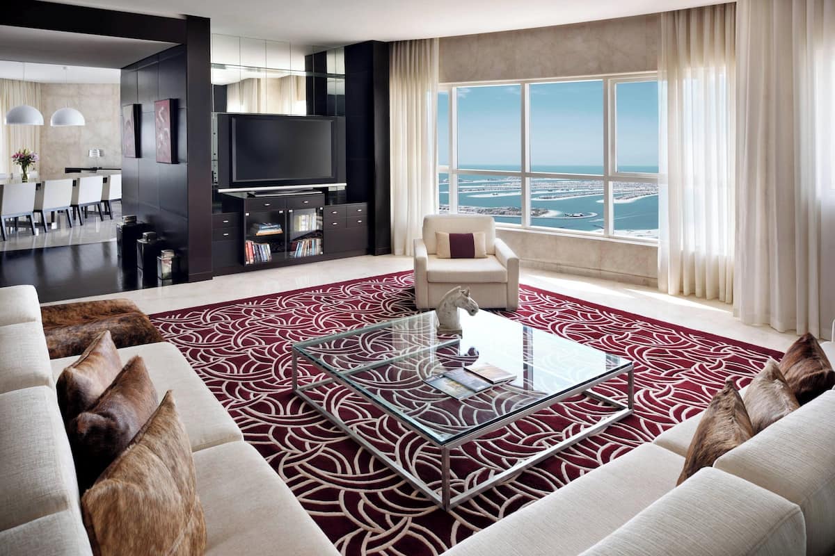 Una sala de estar moderna con una mesa de centro de vidrio, un sofá y vista al mar.