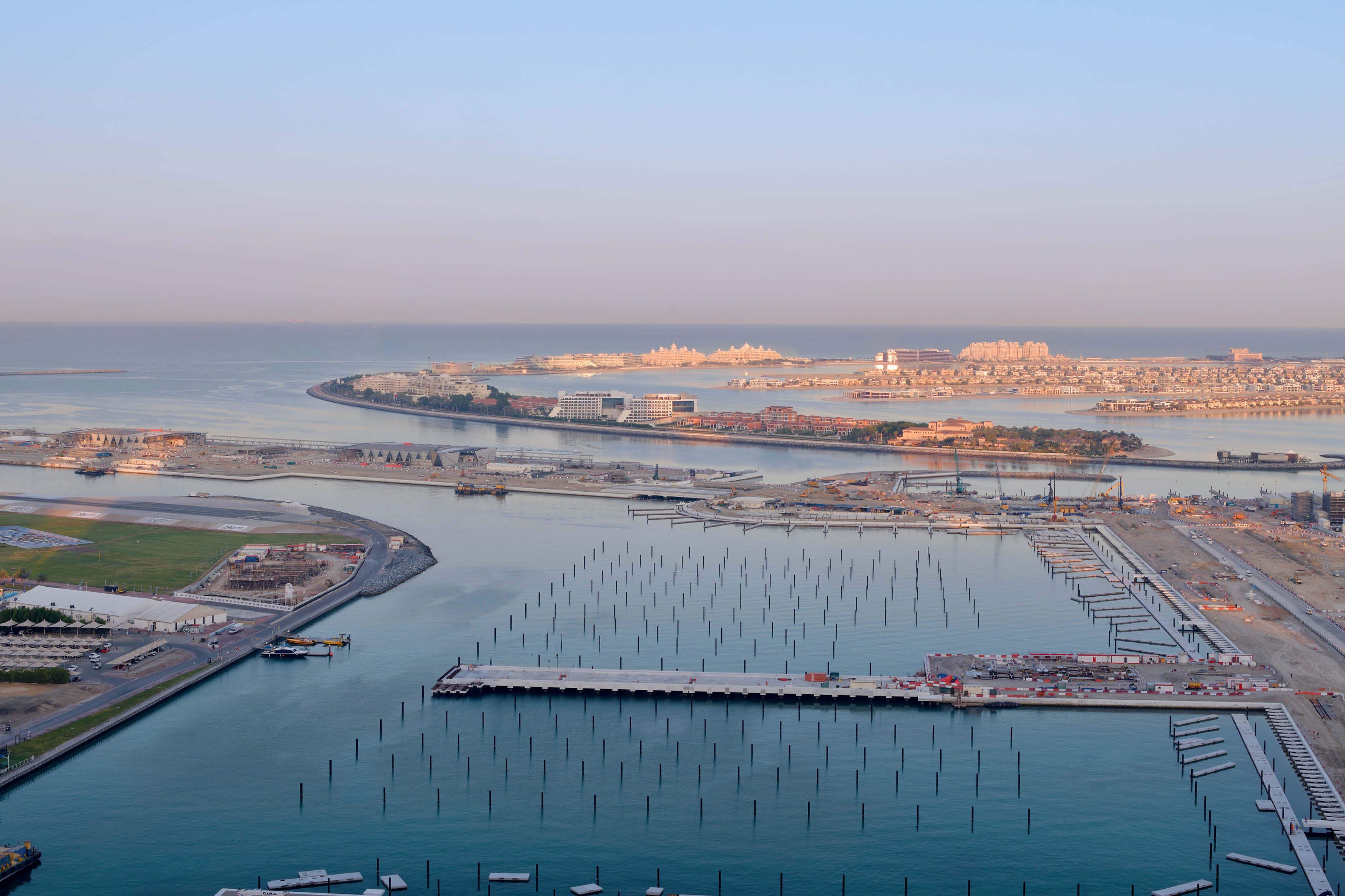 An aerial view of a coastal city with a marina, a large body of water, and a bridge connecting two land masses.