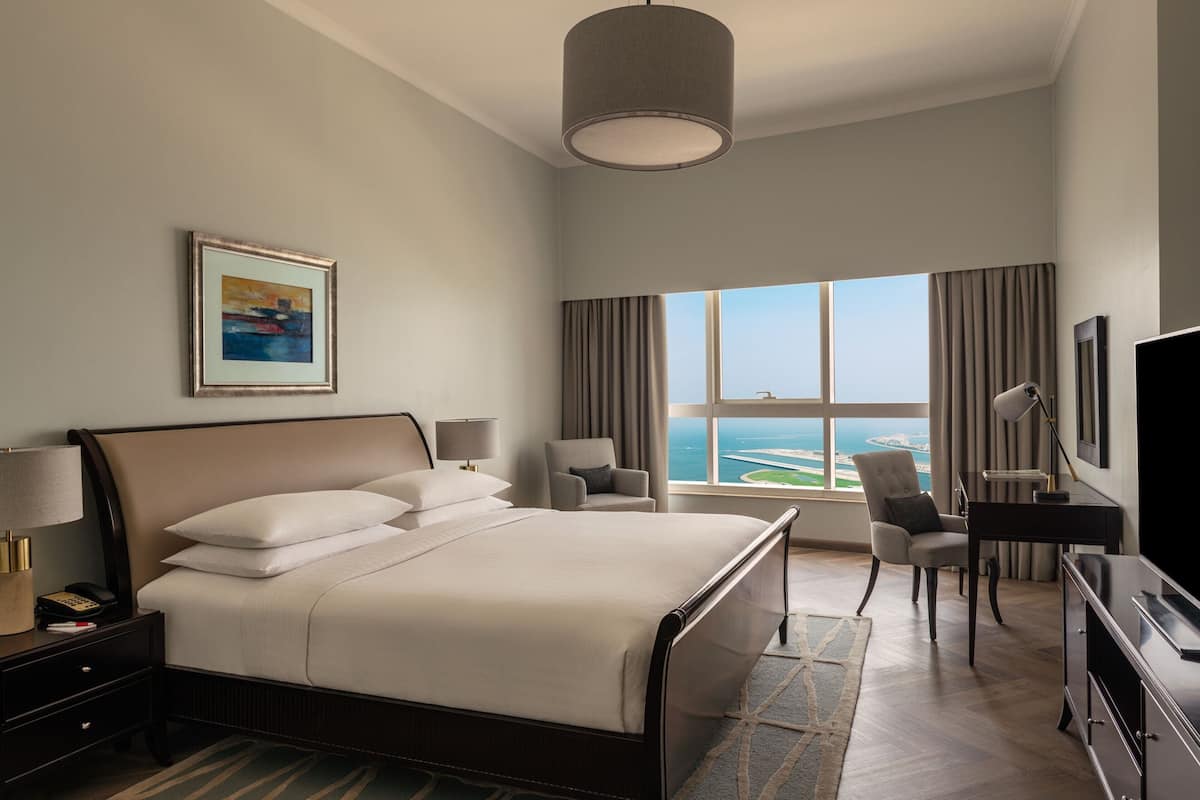 Una habitación de hotel moderna con una cama grande, un escritorio, una silla y un televisor.