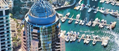 Un hotel de gran altura con una cima esférica distintiva, un puerto deportivo con numerosos barcos y edificios urbanos circundantes.