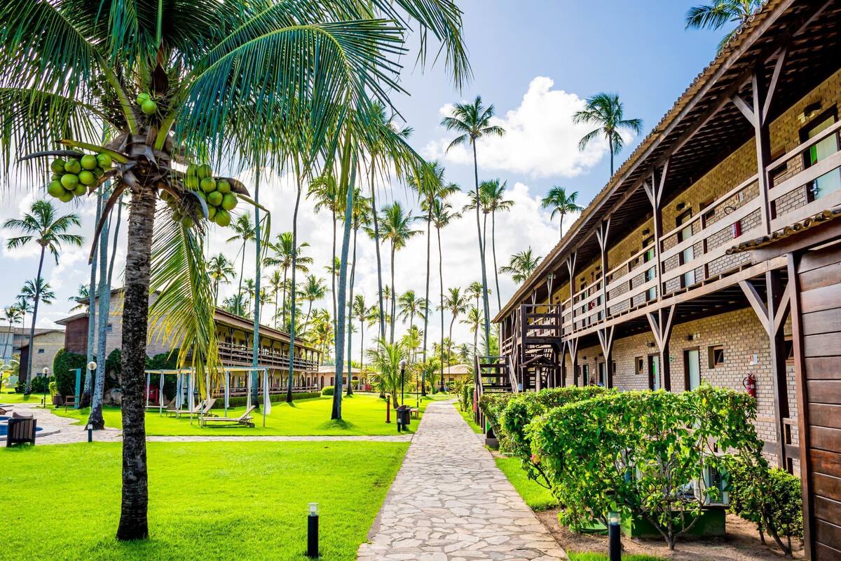 A resort with a paved walkway, palm trees, and a building with multiple balconies.