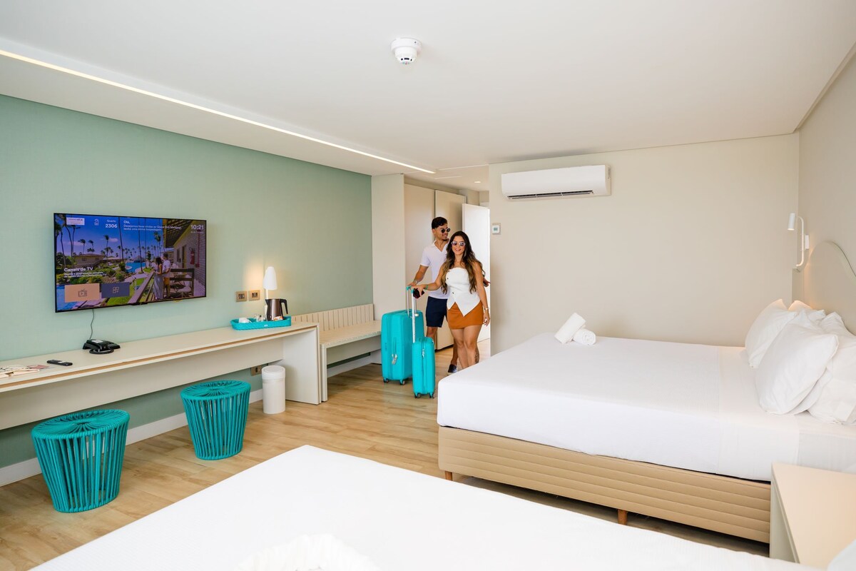 A hotel room with a bed, a desk, a TV, and a bathroom.
