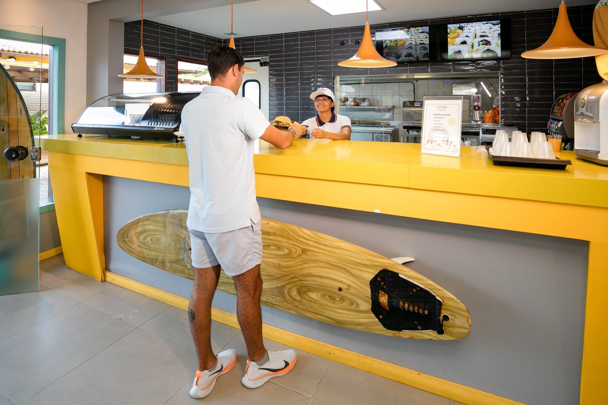 A counter with a yellow countertop and a wooden surfboard decoration.