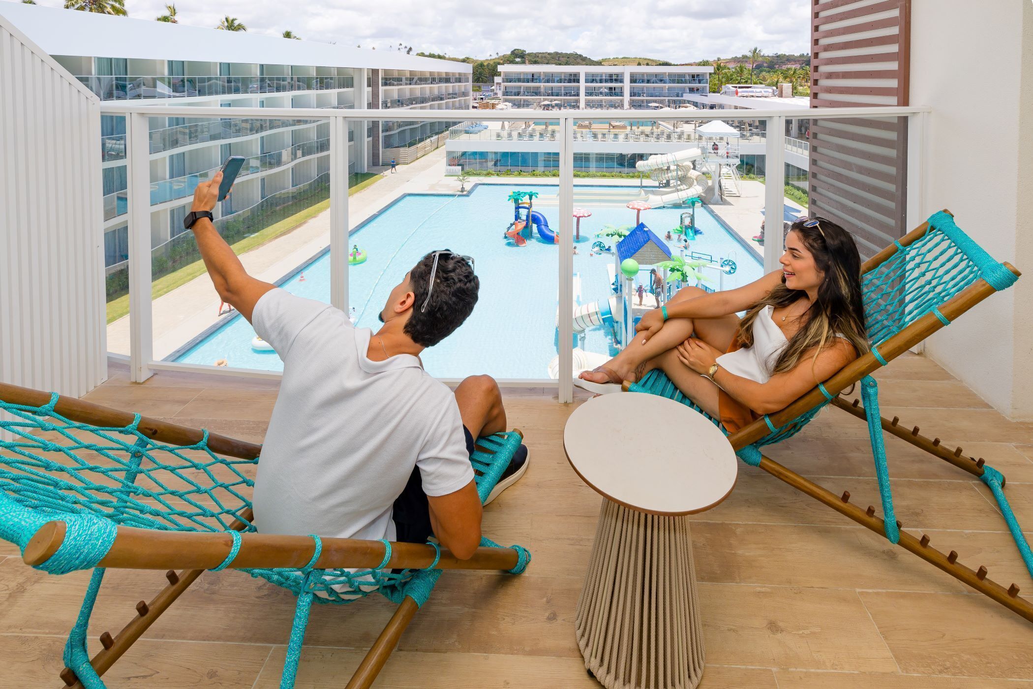 A balcony with two hammocks, a pool, and a water park view.