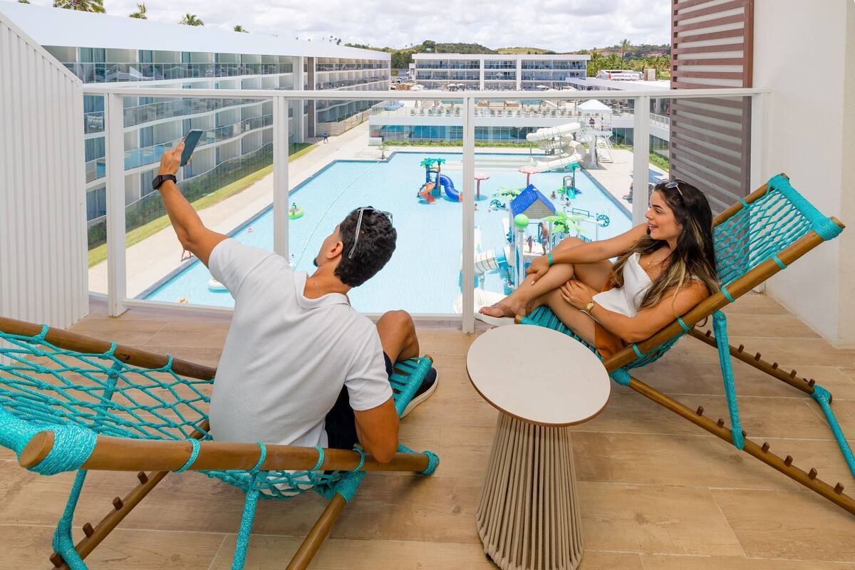 A balcony with two hammocks, a pool, and a water park view.