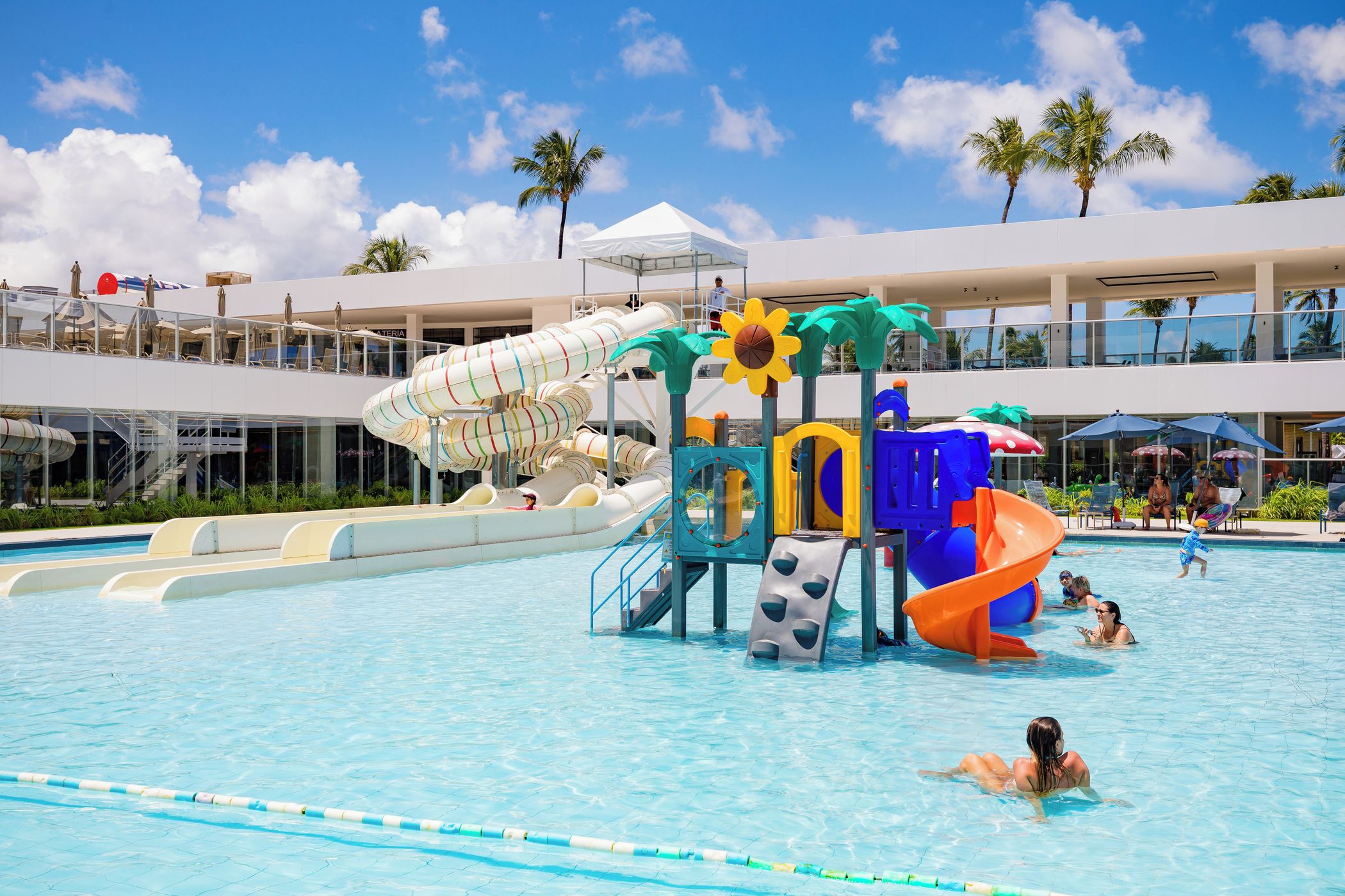 A swimming pool with multiple water slides and a sun-shaped play structure.
