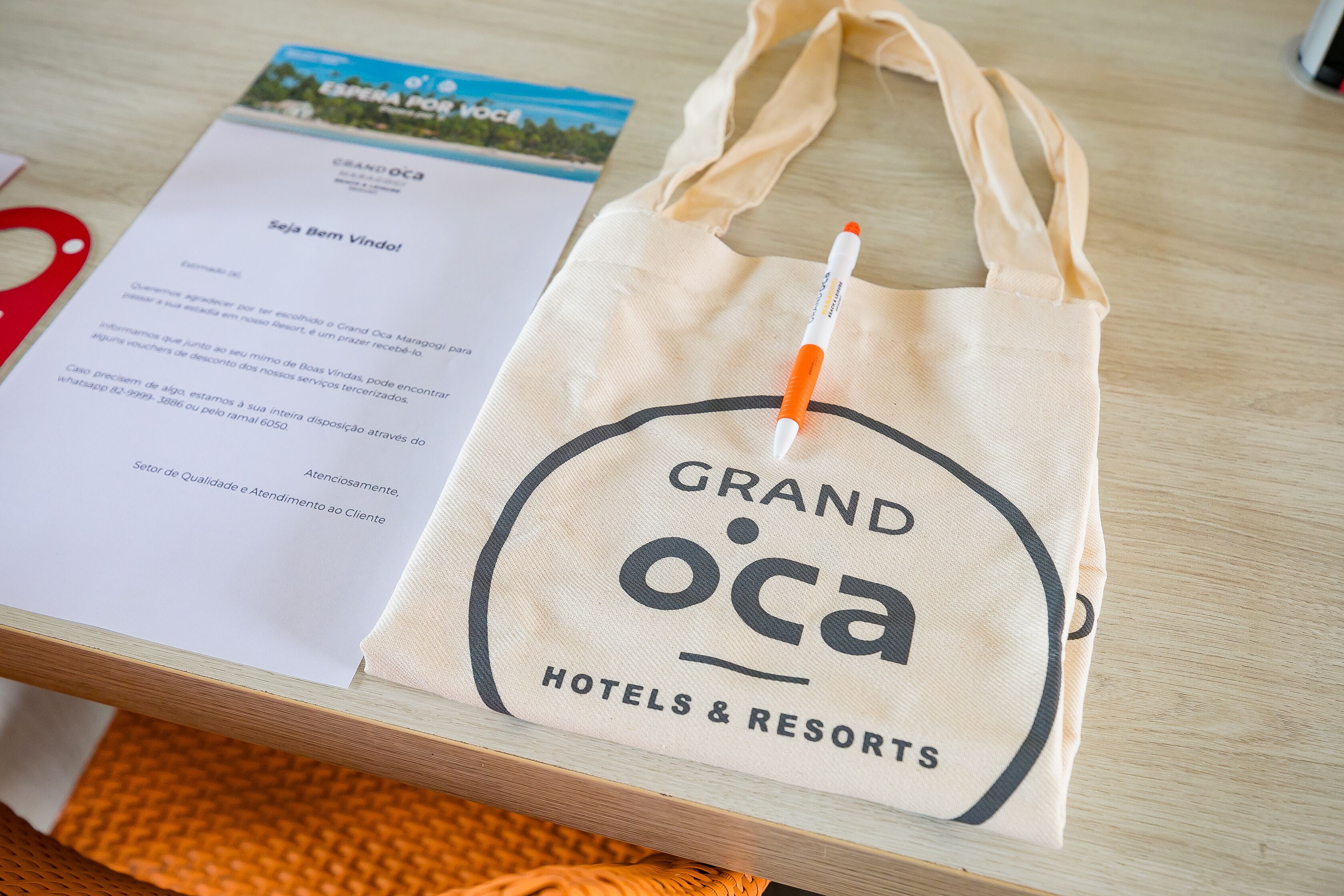 A hotel bag with the logo "GRAND OCA HOTELS & RESORTS" and a receipt with text in Portuguese.