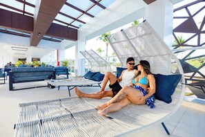 A modern lounge area with wicker lounge chairs, a sofa, and a coffee table. - Grand Oca Maragogi (Maragogi)