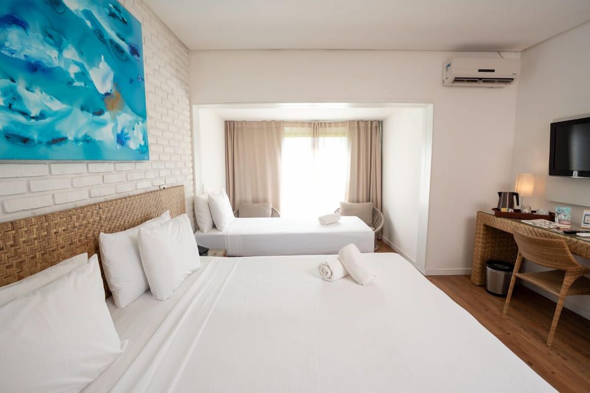 A hotel room with a large bed, a desk, a chair, a television, and a painting on the wall.