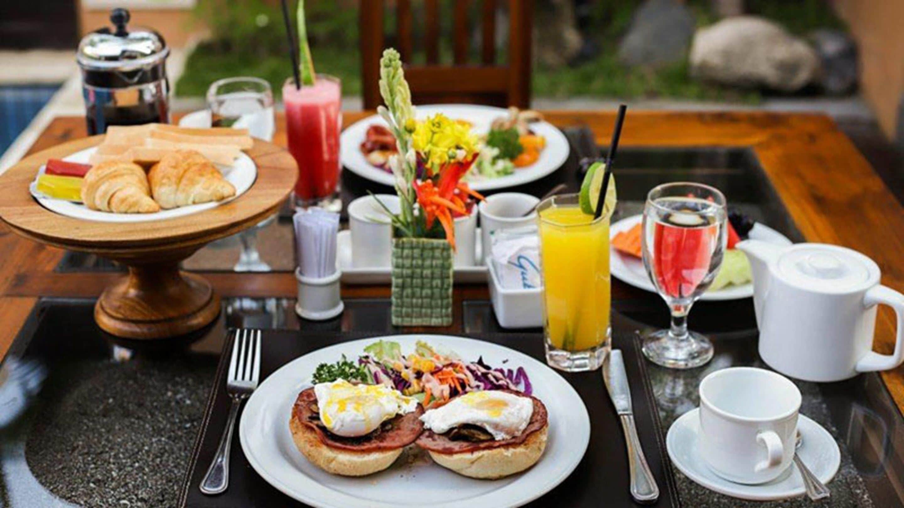 A breakfast table with croissants, eggs, and a salad.