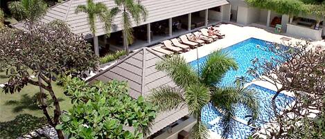 Un hôtel doté d’une piscine, d’un espace extérieur couvert et aménagé, et d’une végétation luxuriante.