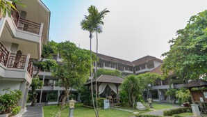 A multi-story hotel with a central courtyard, surrounded by lush greenery and palm trees. - Dewi Sri Hotel (Kuta)
