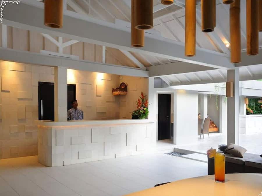 A spacious lobby with a reception desk, a seating area with a table and chairs, and a view of the outdoors.
