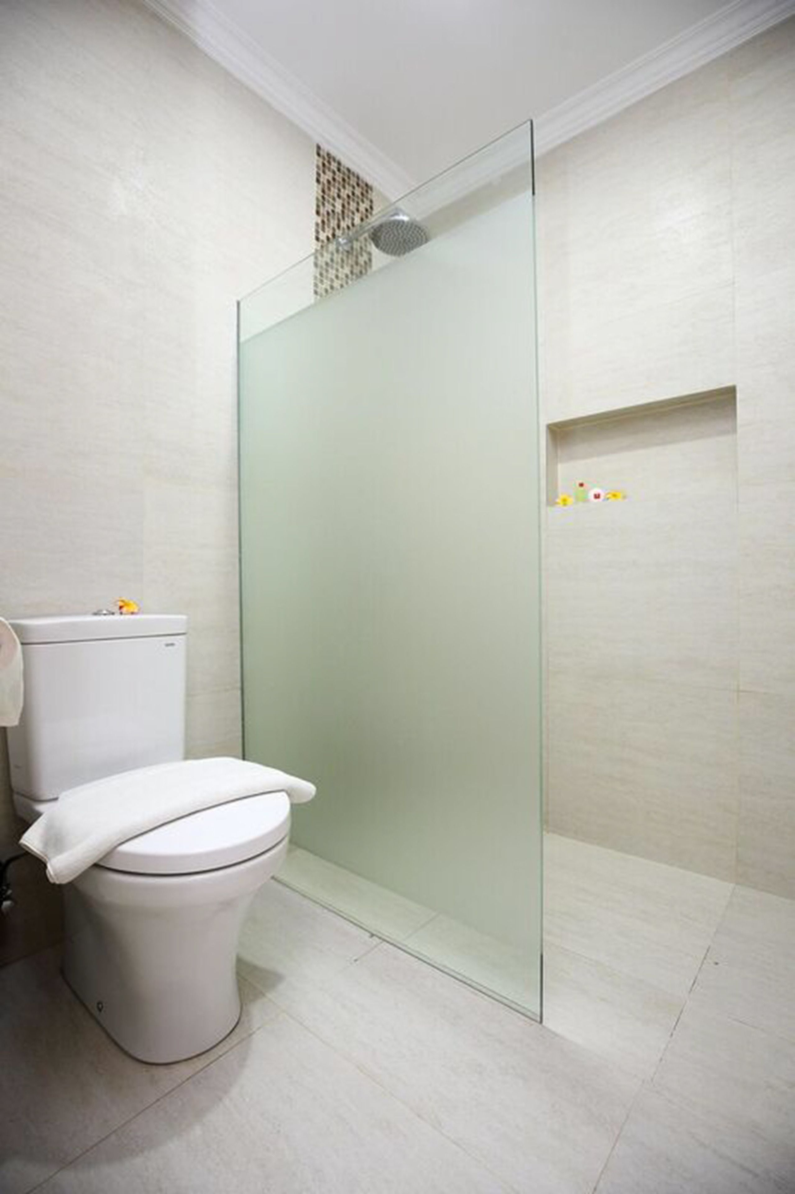 Een moderne badkamer met een douchecabine van glas, een wit toilet en een betegelde vloer.