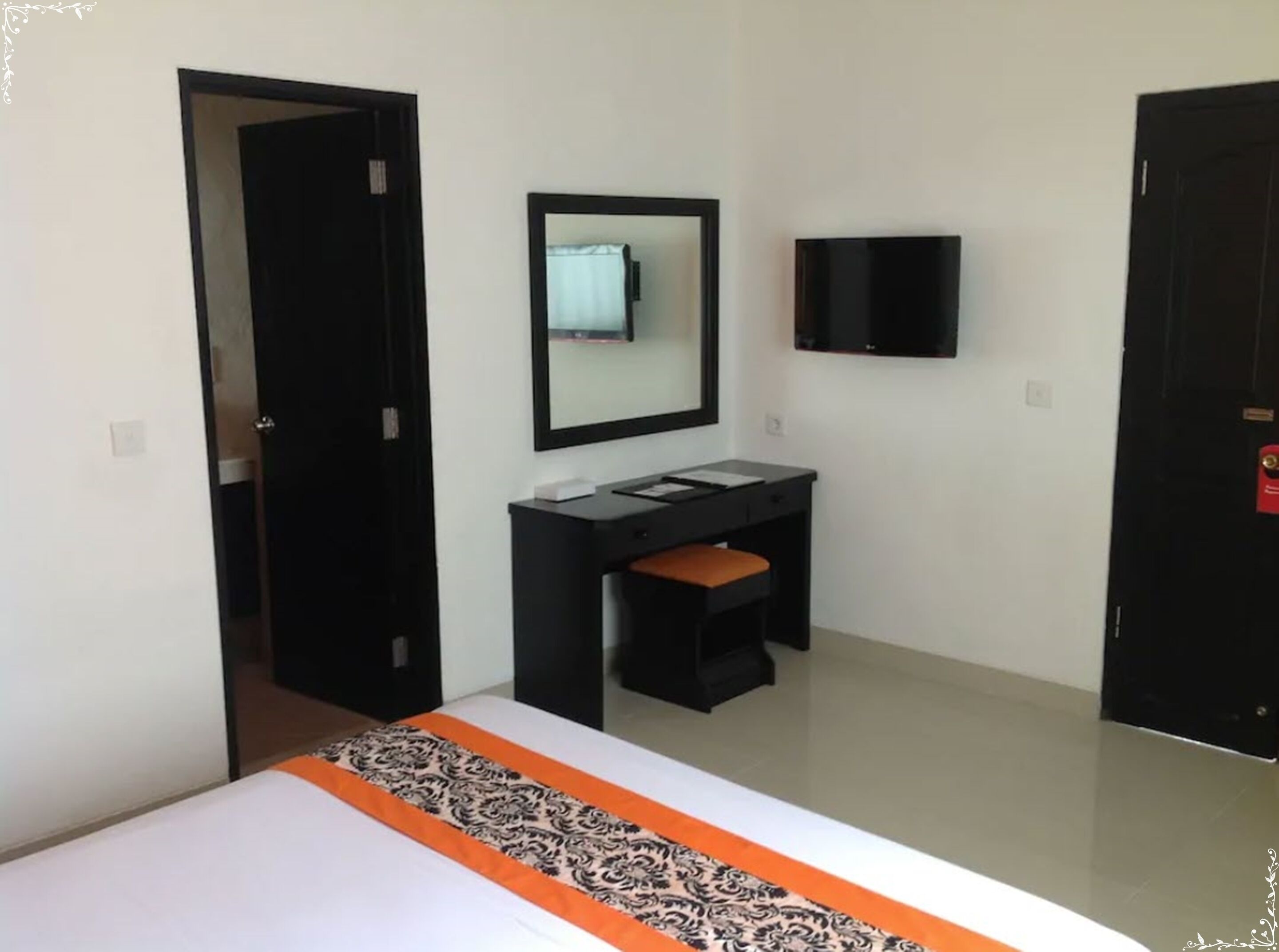 Une chambre d’hôtel comprenant un lit, un bureau avec une chaise, un miroir et un téléviseur.