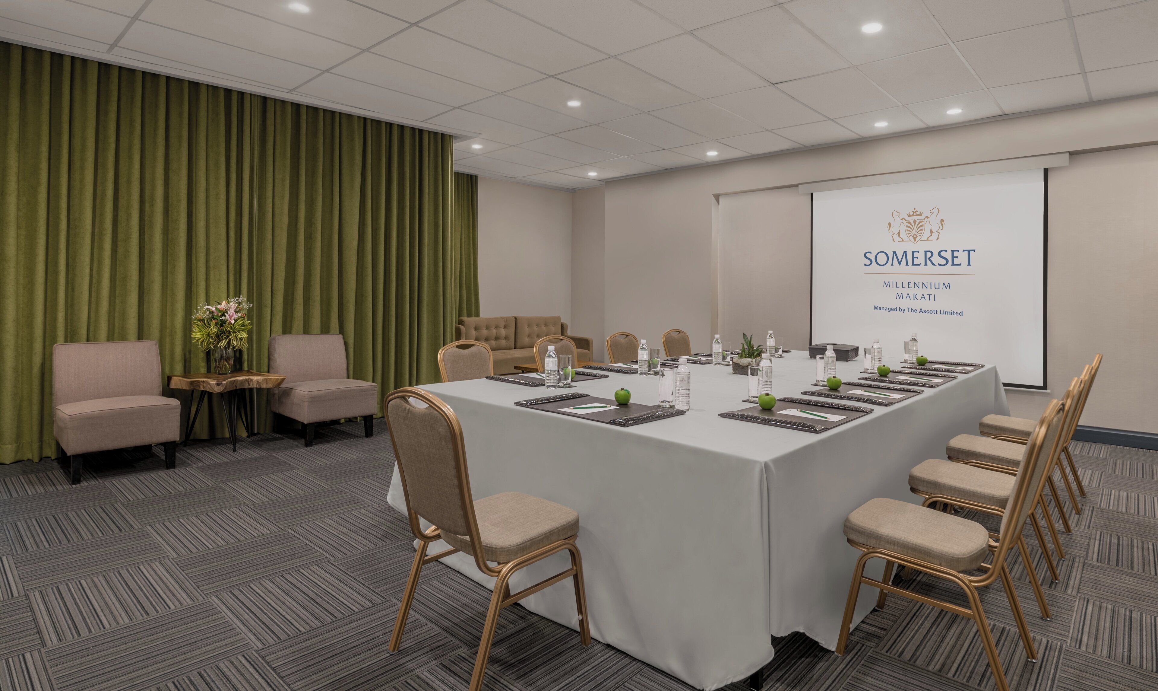 A conference room with a long table, chairs, and a projector screen displaying the Somerset logo.