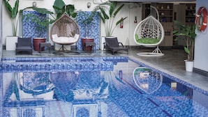 A pool area with mosaic tiles, hanging chairs, and potted plants. - Somerset Millennium Makati (Makati)